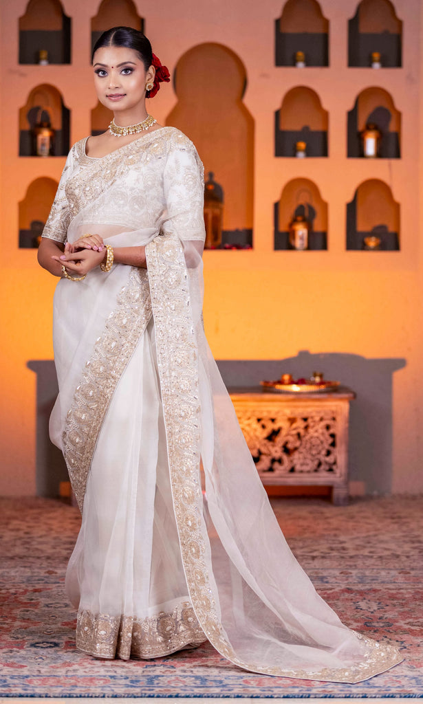 Off White organza saree and blouse embellished with golden zari,pearls and sequence work